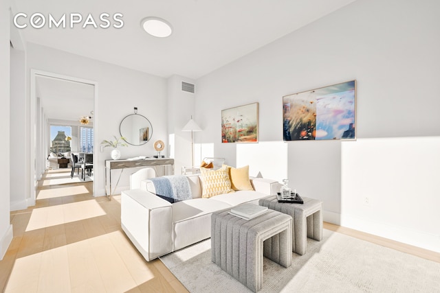 living room featuring visible vents, baseboards, and wood finished floors