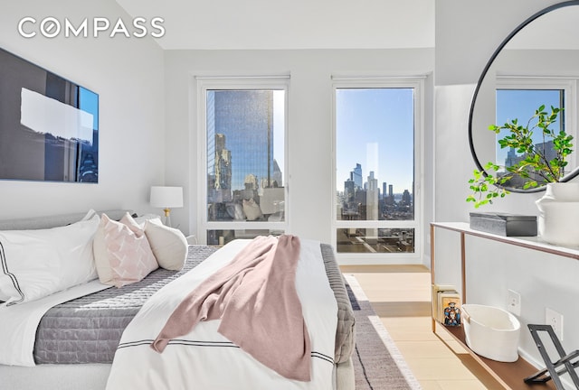 bedroom with a view of city and wood finished floors