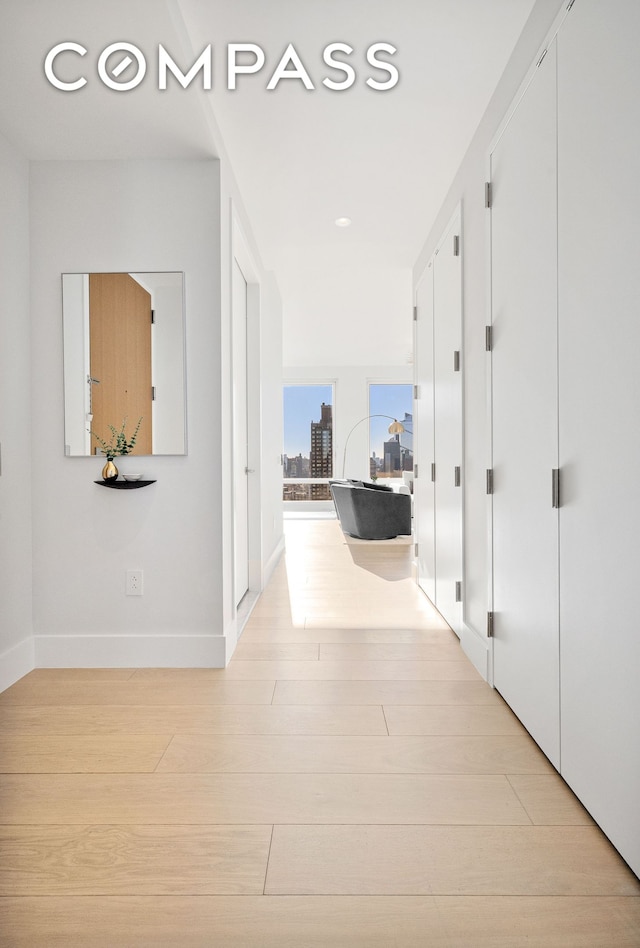 hall featuring light wood-style floors and baseboards