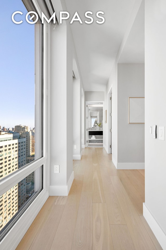 corridor with baseboards and wood finished floors