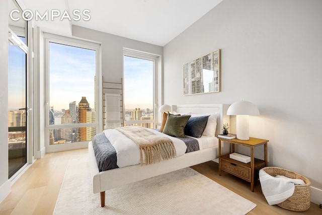 bedroom featuring light wood-style floors, a view of city, and access to outside