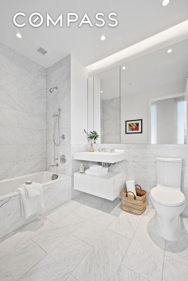full bathroom with recessed lighting, tiled shower / bath, tile walls, and visible vents