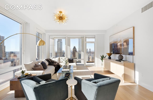 living room featuring visible vents, a view of city, wood finished floors, and a healthy amount of sunlight