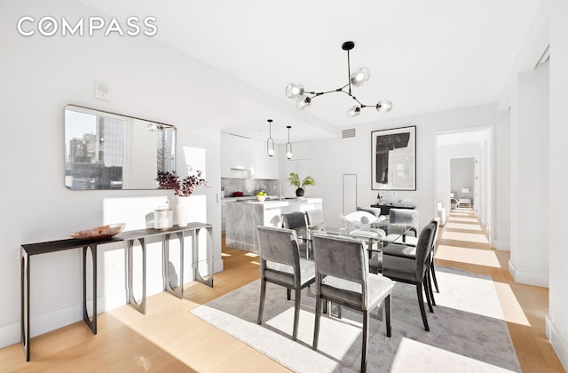 dining room with baseboards, an inviting chandelier, visible vents, and light wood-style floors