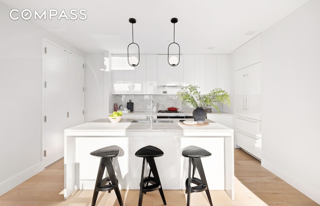 kitchen with modern cabinets, white cabinets, a breakfast bar, and tasteful backsplash