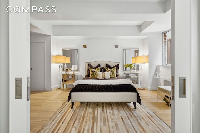 bedroom featuring light wood finished floors and baseboards