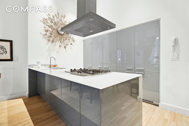 kitchen with a peninsula, modern cabinets, a sink, and island range hood