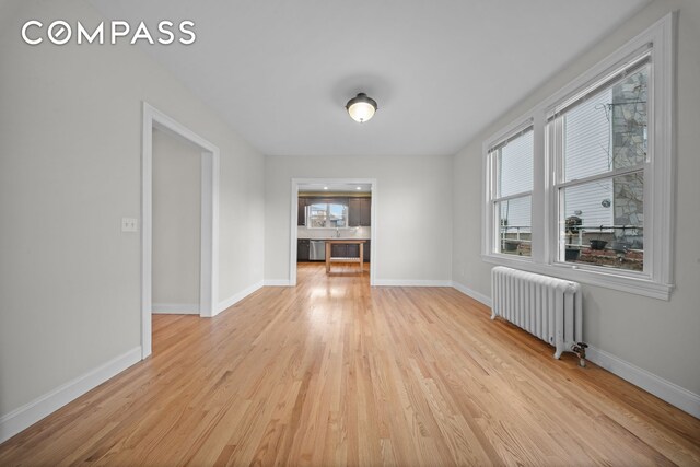 interior space featuring light wood finished floors, radiator heating unit, and baseboards