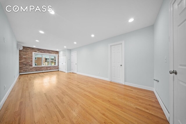 unfurnished living room featuring baseboards, brick wall, light wood-style flooring, and recessed lighting