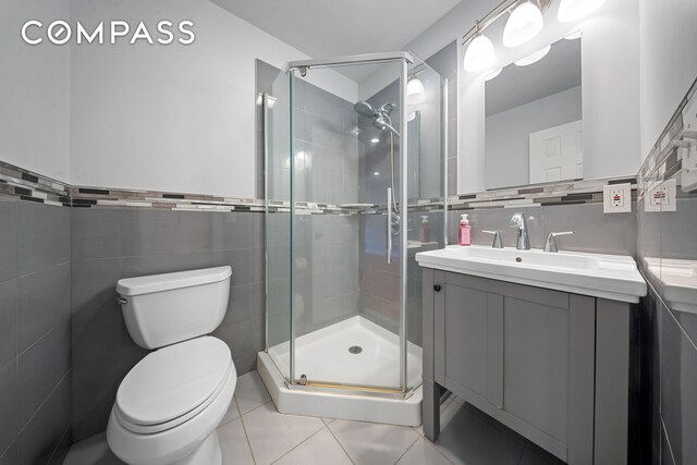 bathroom featuring a stall shower, tile walls, and vanity