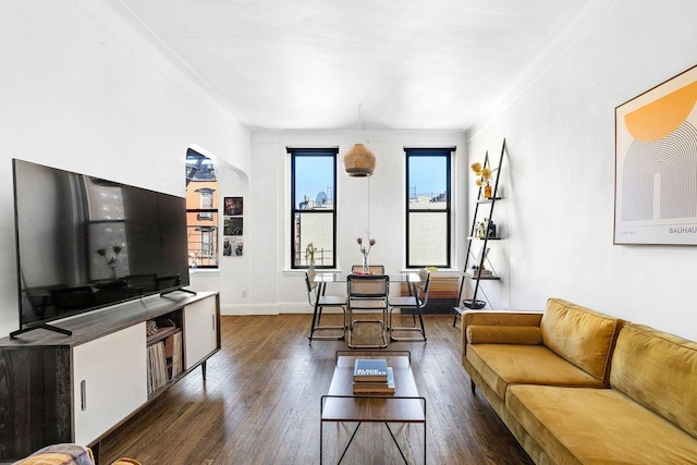 living area with dark wood-style floors, arched walkways, and baseboards