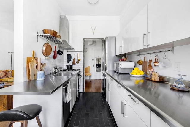 kitchen with dark countertops, white cabinetry, dark wood finished floors, and a breakfast bar area