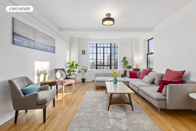 living room with beam ceiling, light wood-style flooring, radiator, and visible vents