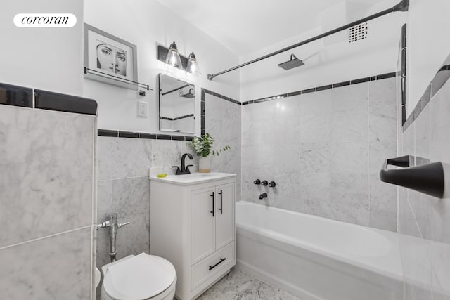 bathroom with toilet, marble finish floor, vanity, shower / washtub combination, and tile walls