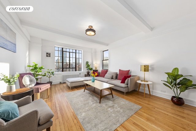 living area featuring visible vents, baseboards, light wood-type flooring, radiator, and beamed ceiling