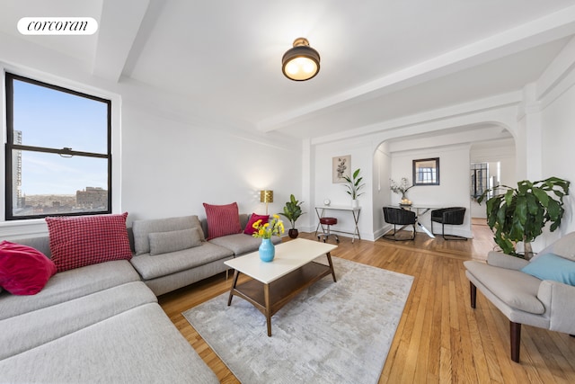 living area featuring arched walkways, visible vents, beamed ceiling, and wood finished floors