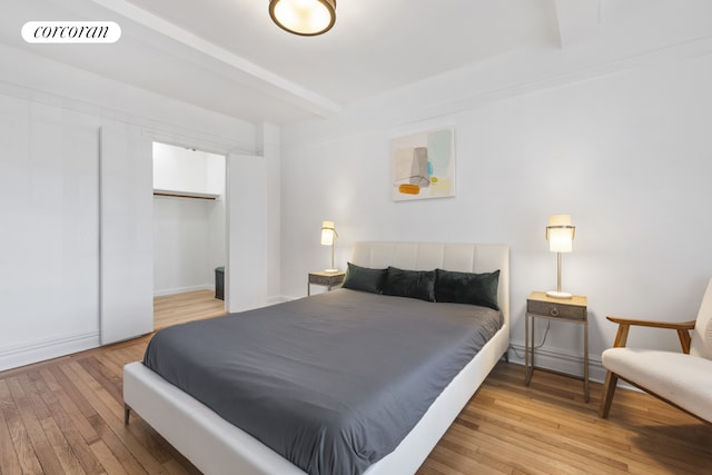 bedroom featuring light wood finished floors, a closet, visible vents, and beamed ceiling