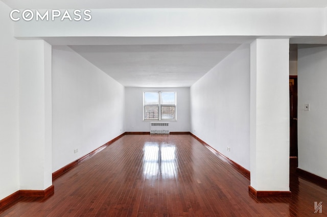 unfurnished room featuring radiator, baseboards, and dark wood-type flooring