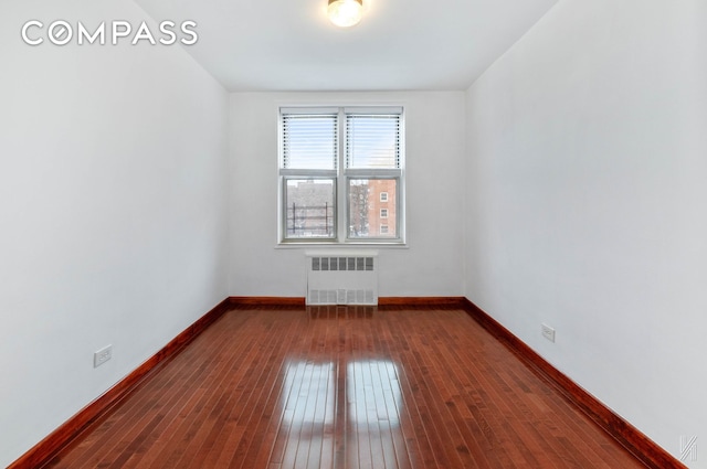 empty room featuring radiator, baseboards, and dark wood finished floors