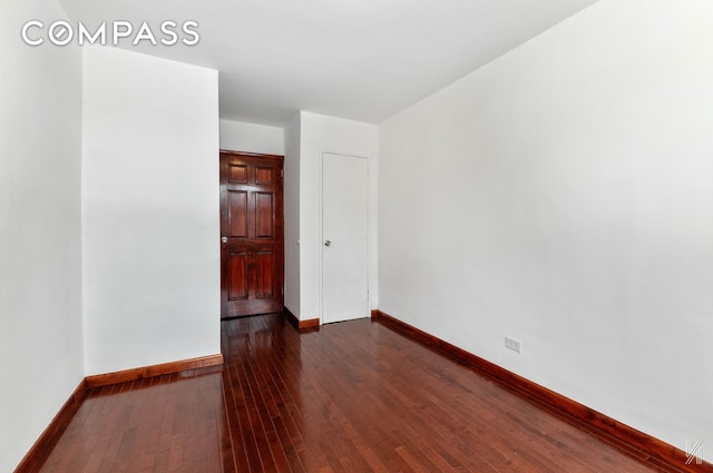 empty room featuring dark wood-style floors and baseboards