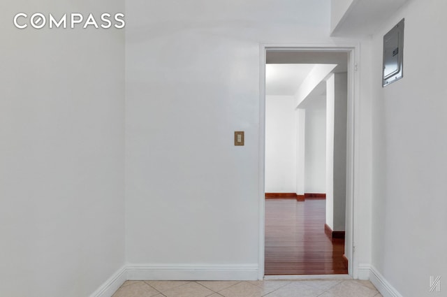 hall featuring light tile patterned flooring and baseboards