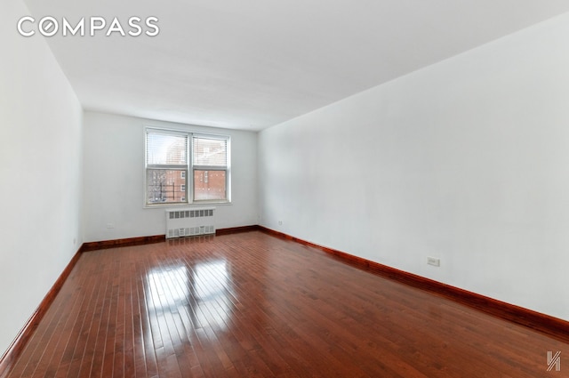 unfurnished room featuring radiator heating unit, baseboards, and wood finished floors