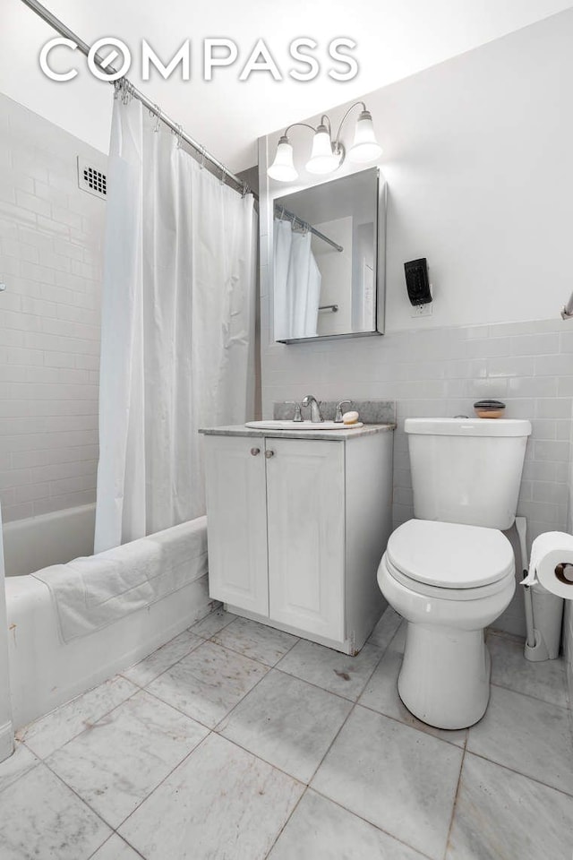 full bathroom with vanity, a wainscoted wall, shower / bath combination with curtain, tile walls, and toilet