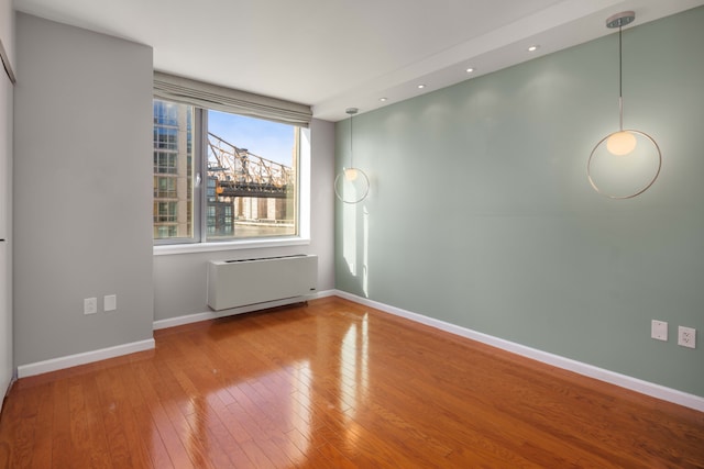unfurnished room with baseboards, radiator heating unit, recessed lighting, and wood-type flooring