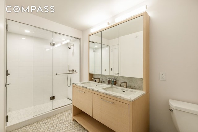 bathroom with decorative backsplash, a stall shower, a sink, and toilet