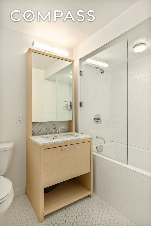 full bath featuring tasteful backsplash, toilet, tiled shower / bath combo, vanity, and tile patterned flooring