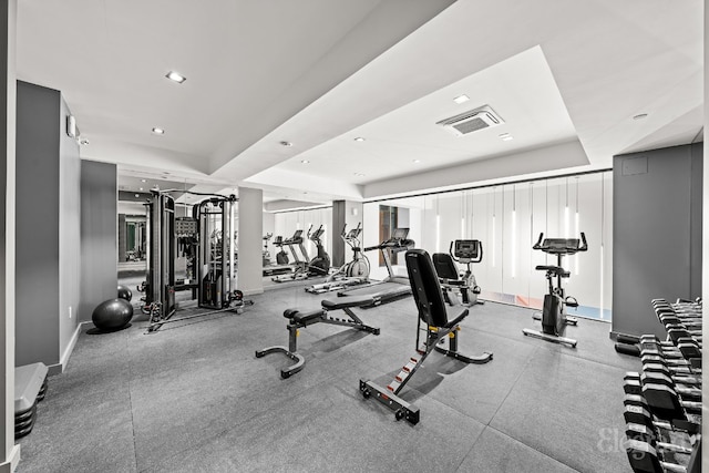 workout area with a tray ceiling, visible vents, baseboards, and recessed lighting