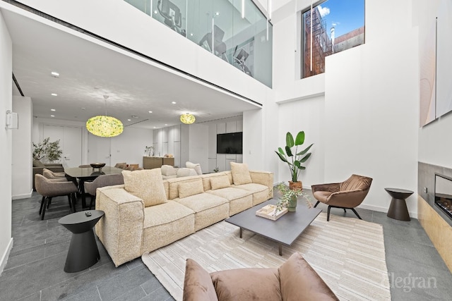 living room with a high ceiling, baseboards, a fireplace, and recessed lighting