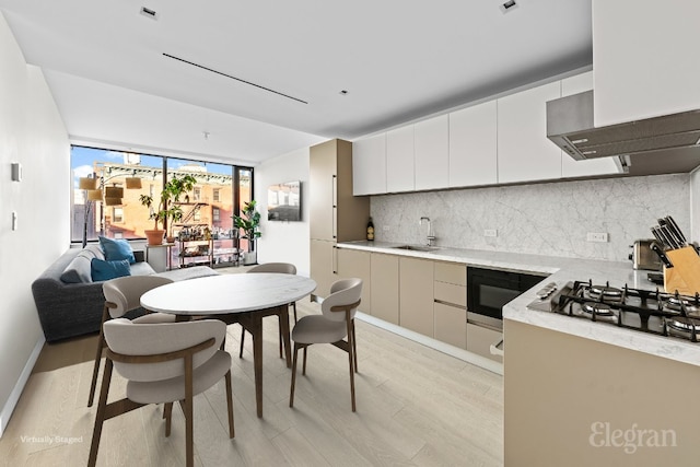 kitchen with light wood-style flooring, modern cabinets, light countertops, and decorative backsplash