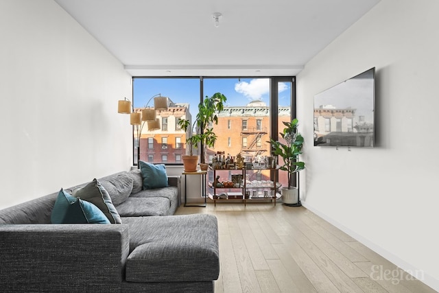 living area with baseboards, a wall of windows, and wood finished floors