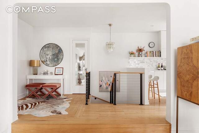 interior space with wood finished floors, an upstairs landing, and an inviting chandelier