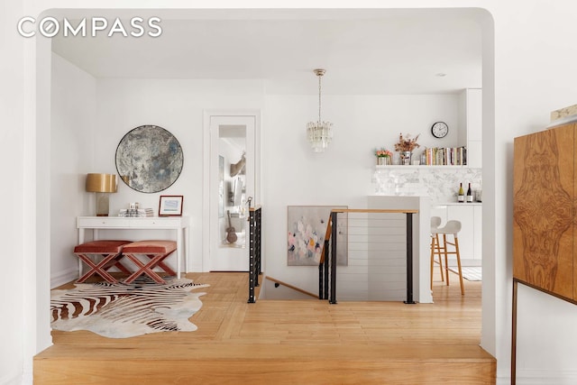 interior space featuring an upstairs landing, an inviting chandelier, and wood finished floors