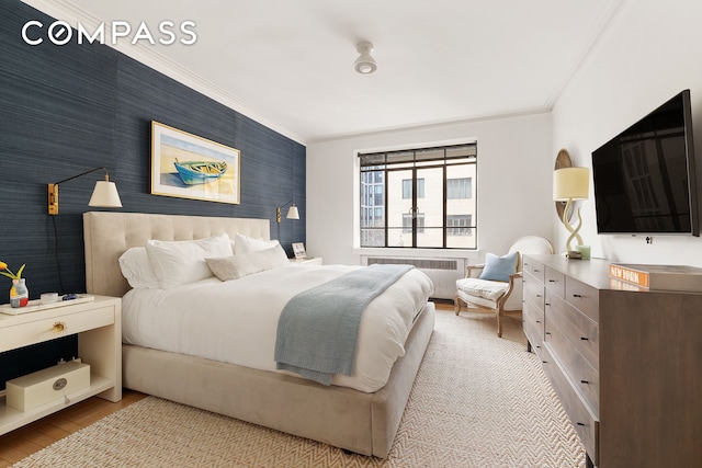 bedroom featuring radiator, wallpapered walls, an accent wall, ornamental molding, and wood finished floors