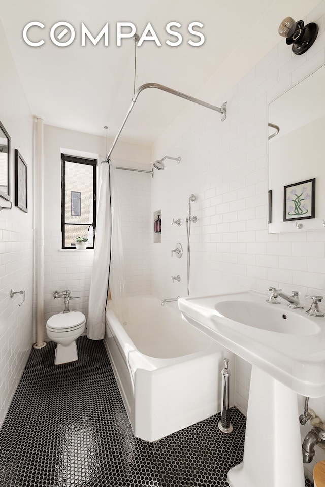 full bath with tile patterned flooring, toilet, shower / bath combo, tile walls, and a sink