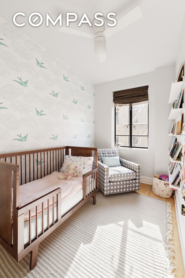 bedroom featuring wallpapered walls, wood finished floors, and baseboards