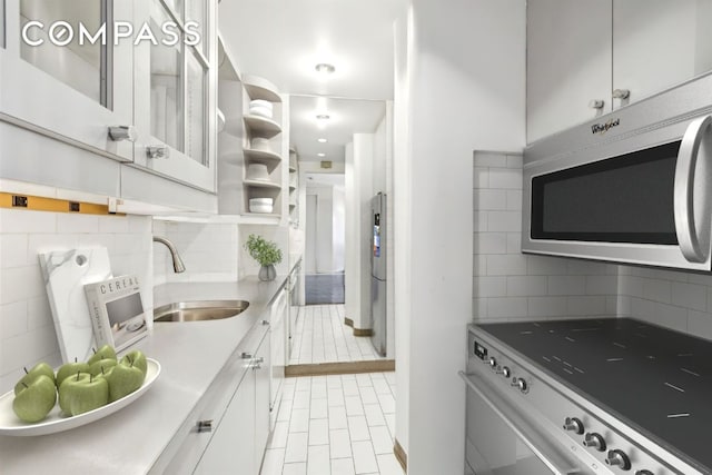 kitchen with white cabinetry, stainless steel appliances, a sink, and light countertops