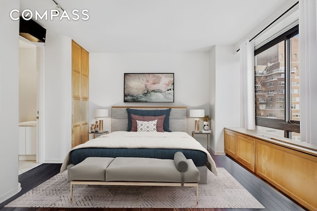 bedroom with baseboards and dark wood-type flooring