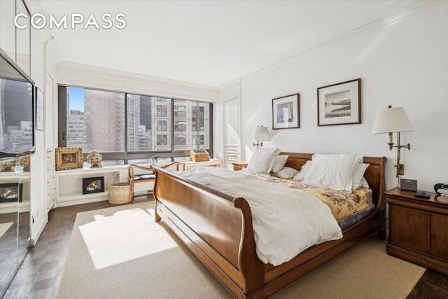 bedroom featuring a view of city, crown molding, and a lit fireplace