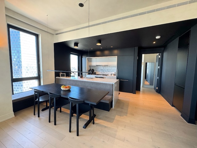 kitchen featuring a center island with sink, white cabinets, light wood-style flooring, modern cabinets, and light countertops