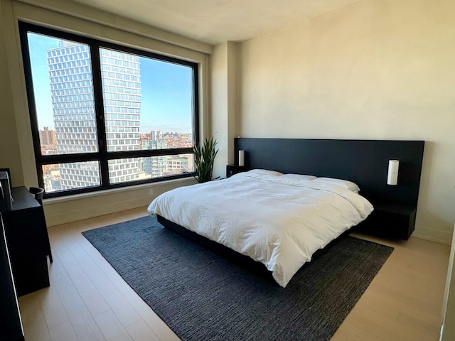 bedroom featuring a view of city, wood finished floors, and baseboards