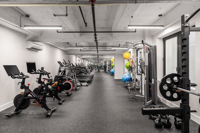 workout area featuring baseboards and a wall unit AC