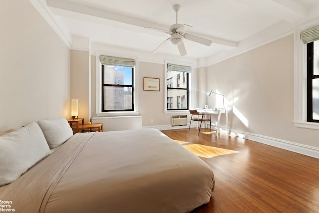 bedroom with wood finished floors, a ceiling fan, baseboards, a wall mounted AC, and beam ceiling