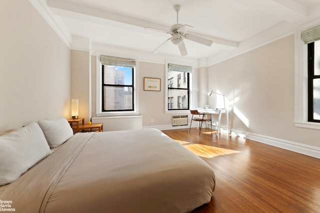 bedroom featuring beam ceiling, a ceiling fan, wood finished floors, a wall unit AC, and baseboards