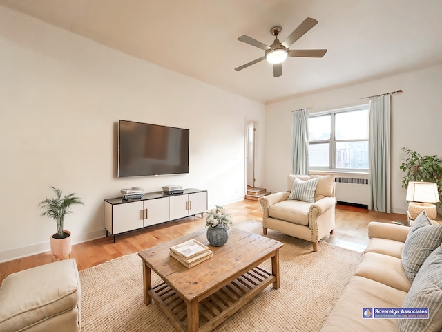 living room with ceiling fan, radiator heating unit, light wood-type flooring, and baseboards