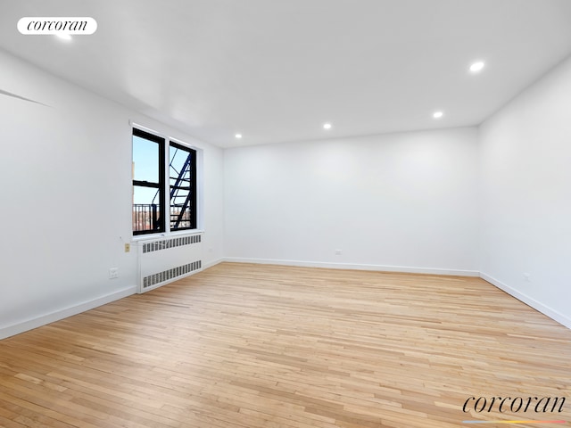 unfurnished room with light wood finished floors, visible vents, baseboards, radiator heating unit, and recessed lighting