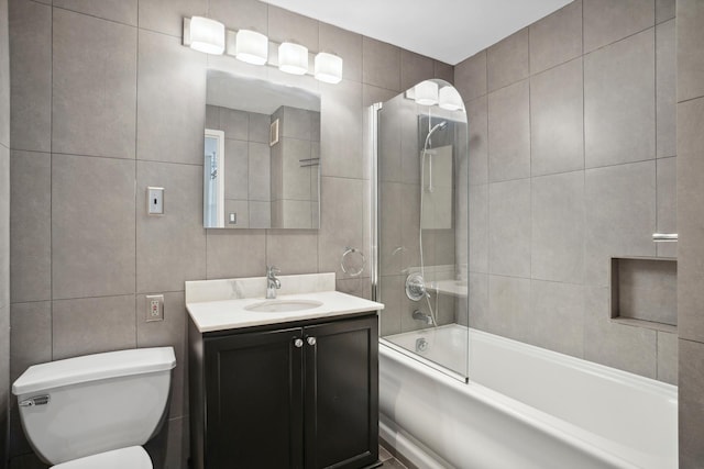 bathroom featuring toilet, tile walls, washtub / shower combination, and vanity